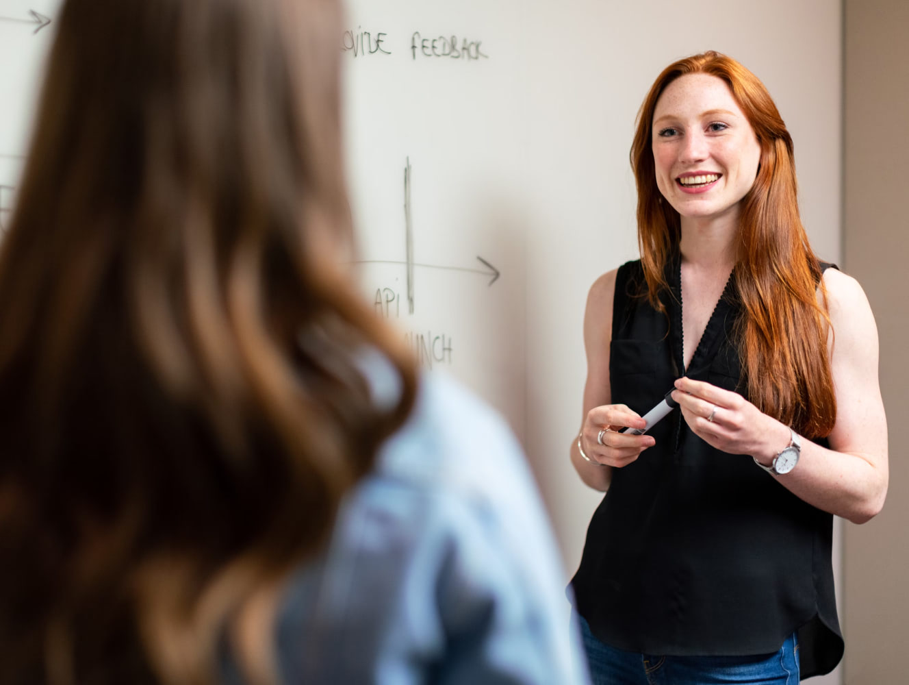 Teacher standing at a whiteboard answering a student's question